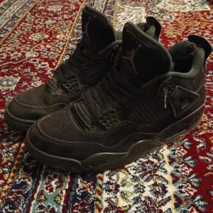 Svarta Nike Air Jordans 4 - Säljer ett par svarta Nike Air Jordans med klassisk design och snörning. Skorna har en robust sula och ikonisk logga på plösen. Perfekta för sneakerheads som älskar stil och komfort. Är också söndriga på båda skor där bakom. Därför säljer jag de billigt.