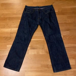 Mörkblå jeansbyxor - Snygga mörkblå jeansbyxor med klassisk design och raka ben. De har en knapp och dragkedja framtill samt fem fickor. Perfekta för en avslappnad stil.