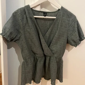 Grön omlottblus från Vero Moda - Snygg mörkgrön omlottblus med korta ärmarfrån Vero Moda. Perfekt för både vardag och speciella tillfällen. Passar även väldigt bra i sommar💗