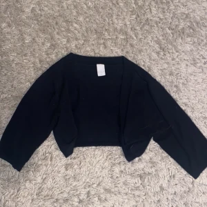 Svart bolerotopp från Vila - Snygg svart bolerotopp från Vila. Perfekt för att lägga till en stilren touch till din outfit. Den har en enkel design med långa ärmar och är tillverkad i ett mjukt material.