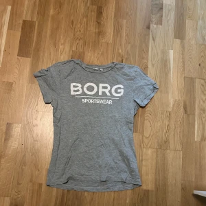 Grå t-shirt från Björn Borg - Säljer en grå t-shirt från Björn Borg med texten 'BORG SPORTSWEAR' tryckt på framsidan. T-shirten är kortärmad och tillverkad i ett mjukt material.