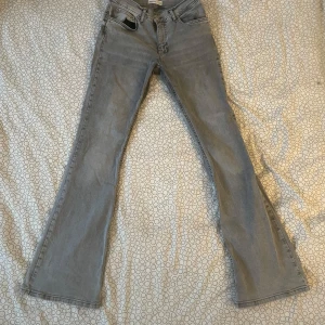 Grå bootcut jeans från Gina Tricot - Snygga grå bootcut jeans från Gina Tricot. De har en klassisk femficksdesign och är perfekta för en avslappnad stil. Jeansen har en knapp och dragkedja framtill. Mid-waist. för små för mig. Ursprungligt pris: 499kr