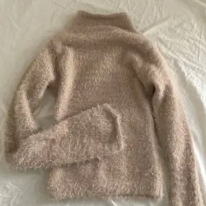 Supermysig beige fluffig tröja som är perfekt för kyliga dagar. Den har en tight passform och är croppad, vilket gör den både trendig och bekväm. Långärmad och gjord i ett mjukt material som känns som en kram. Perfekt för höst och vinter!