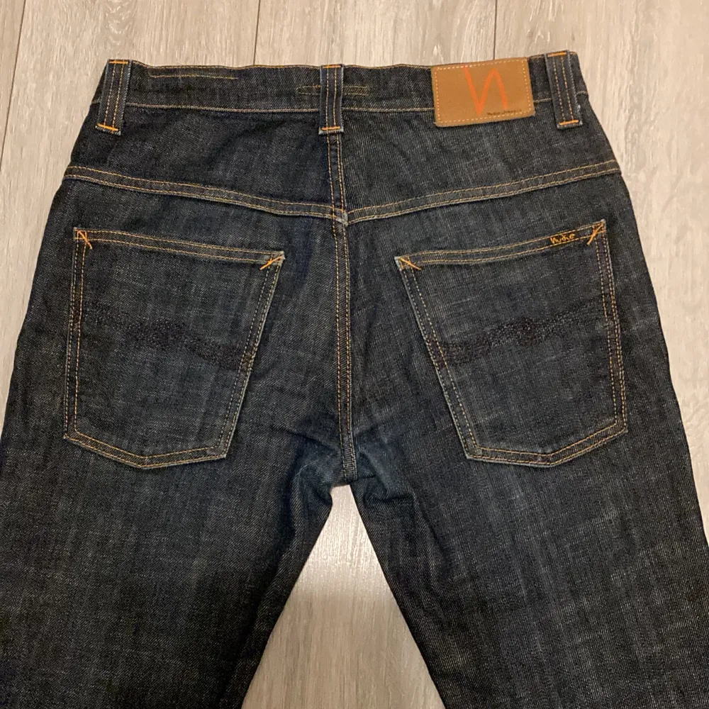 Säljer ett par snygga mörkblå jeans från Nudie Jeans i storlek W31 L32. De har en klassisk femficksdesign med orange sömmar och en bekväm passform. Perfekta inför vintern och är väldigt sköna och varma. Jeans & Byxor.