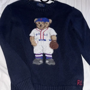 Mörkblå tröja med björn från Polo Ralph Lauren - Säljer en mörkblå tröja från Polo Ralph Lauren med en söt björn i baseballkläder på framsidan. Storlek xs-s/14-16 år. Tröjan har långa ärmar och är i mycket bra skick. Perfekt för höst och vinter! Pris kan diskuteras!🐻⚾