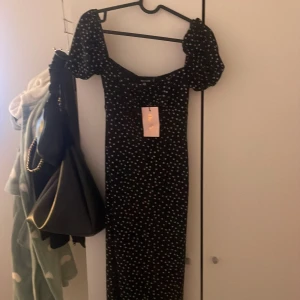 Svart prickig klänning från Missguided - Säljer en superfin svart klänning från Missguided med vita prickar. Den har puffiga kortärmar och en tight passform som ger en snygg siluett. Perfekt för både fest och sommarhäng! Klänningen är i nytt skick och har fortfarande taggen kvar. Kom provat för fler bilder.