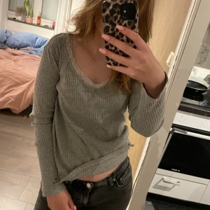 Grå ribbad tröja från Capri Collection - Säljer en superfin grå ribbad tröja från Capri Collection. Den har en vacker spetsdetalj vid halsringningen och är långärmad. Perfekt för både vardag och lite finare tillfällen. Passar bra till jeans eller kjol!