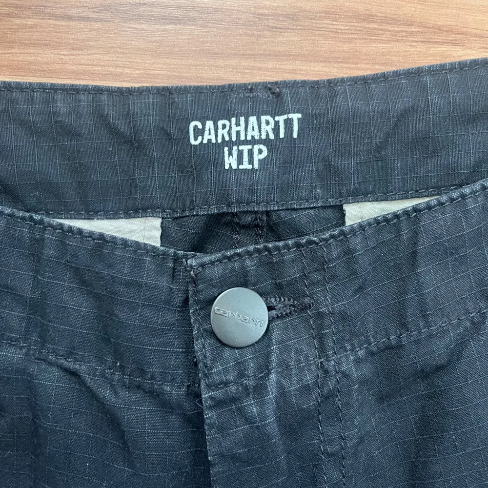 Säljer ett par svarta cargobyxor från Carhartt WIP i helt ok skick. Byxorna har flera praktiska fickor och en knappstängning. Perfekta för en casual look eller utomhusaktiviteter. Storleken är inte specificerad, men de ser ut att ha en normal passform.. Jeans & Byxor.