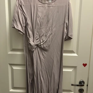 Ljuslila klänning med knytdetalj - Säljer en superfin ljuslila klänning från H&M i storlek 40. Den har en snygg knytdetalj framtill och korta ärmar.Materialet känns mjukt och bekvämt. Baksidan har en liten knappdetalj vid nacken. Passar både till vardag och fest! Kommer från djur och rökfritt hem.