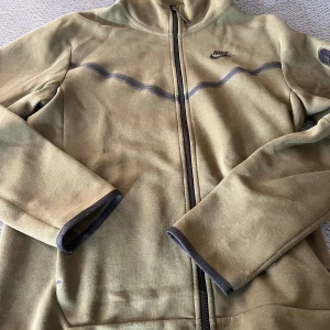 Nike tech fleece - Olivgrön jacka från Nike - Säljer en olivgrön jacka från Nike i bra skick. Den har en dragkedja framtill och långa ärmar. Perfekt för höst och vår med sin sportiga stil. Jackan har en diskret Nike-logga på bröstet och en huva för extra skydd mot väder. En liten fläck på bröstet (se bild) som kanske går bort med fläckborttagningsmedel.