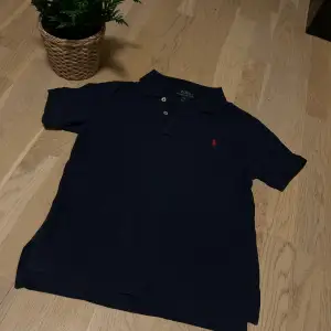 Säljer en klassisk mörkblå pikétröja från Ralph Lauren i storlek S. Tröjan har en broderad röd logga på bröstet och knappar vid kragen. Perfekt för en stilren och avslappnad look. Använd få gånger och i mycket bra skick. Skicka gärna prisförslag. Barn Small inte vuxen.