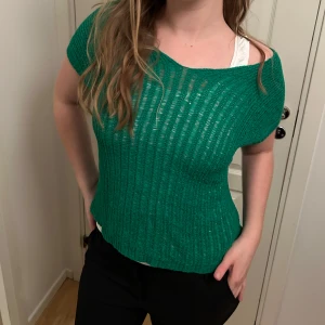 Grön stickad topp från Club L - Säljer en snygg grön stickad topp/väst från Club L. Den har en v-ringad design och korta ärmar. 