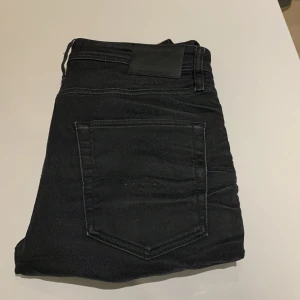 Svarta jeans från Jack & Jones - Säljer ett par svarta jeans från Jack & Jones i modellen Comfort/Mike. De är i bra skick och har en klassisk femficksdesign. Perfekta för både vardag och fest. Passar bra till när du vill klä upp dig lite. Sköna och stilrena!