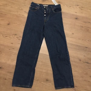 Mörkblå Levis jeans - Säljer ett par mörkblå jeans från Levi’s i mycket bra skick. De har en klassisk femficksdesign och knappar framtill. Använda Max 2 gånger men har en liten reva på baksidan, se bild. Är dock lätt och laga om man vill 