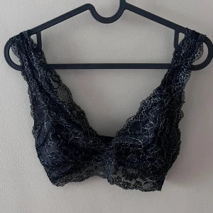 Svart spets bralette - Säljer en elegant svart spets bralette i mycket bra skick. Den har ett vackert blommigt mönster och är perfekt för att lägga till en touch av lyx till din outfit. Braletten är bekväm och stilren, idealisk för både vardag och speciella tillfällen.