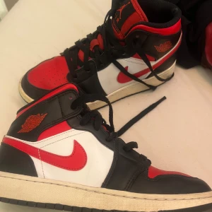 Nike Air Jordans i svart, röd och vit - Säljer ett par klassiska Nike Air Jordans i svart, röd och vit. Skorna har en ikonisk design med snörning och är i bra skick. Perfekta för både vardag och fest! Pris kan diskuteras. Säljer för har tröttnat på de och vill bli av med de snabbt