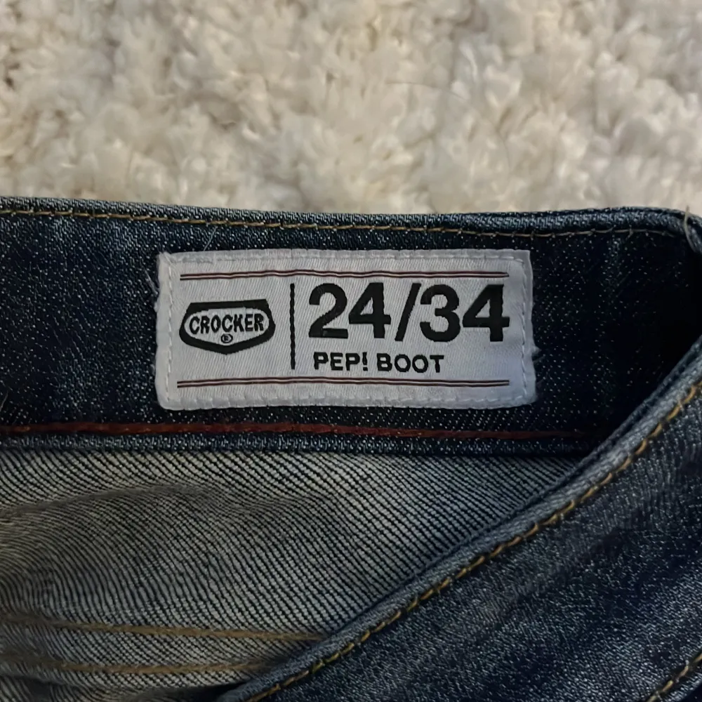 Säljer mina skitsnygga mörkblå lågmidjade bootcut jeans från Crocker i storlek 24/34. De är i mycket bra skick och endast använda ett fåtal gånger då de är försmå för mig. Midjemåttet är 35 cm rak över och innerbenslängden är 88 cm. Men jag som är 162 cm tycker längden var bra då de la sig snyggt vid fötterna även om du är kortare. På sista bilden ser du även att de e väldigt snygga detaljer på färgen i jeansen. Det är bara fråga om ni har några funderingar❤️. Jeans & Byxor.