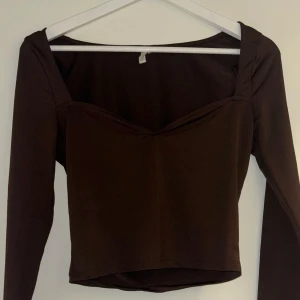 Brun festtopp - Brun tröja med snygg skärning vid bröstet. I brunt glansigt material, och lite croppad