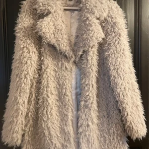 Beige pälsjacka - Säljer en supermysig beige pälsjacka i storlek 36. Den är perfekt för kalla höst- och vinterdagar. Jackan har en fluffig textur och är långärmad, vilket gör den både stilren och varm. Insidan är fodrad med ett glansigt material för extra komfort. Perfekt för att hålla stilen i kylan! 🧥✨