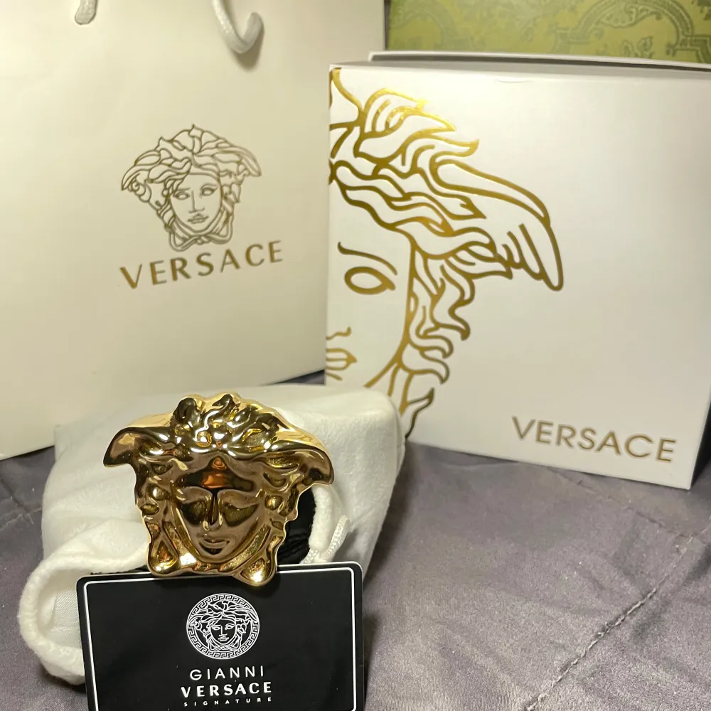 Säljer ett snyggt svart skärp från Versace med ett stort, ikoniskt guldspänne i form av Medusa. Perfekt för att ge din outfit en lyxig touch. Skärpet är i nytt skick och kommer med originalförpackning och påse. Passar både till fest och vardag.. Accessoarer.