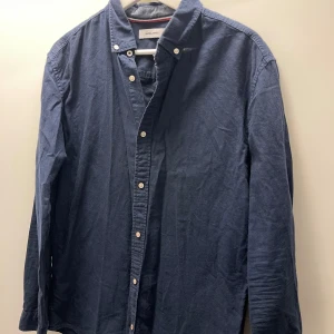 Mörkblå linneskjorta - Säljer en snygg mörkblå skjorta från Jack & Jones i bra skick. Skjortan har långa ärmar och knappar fram. Perfekt för både vardag och fest! Passar bra till jeans eller chinos för en avslappnad men stilren look.