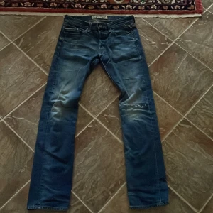 Blå jeans från Replay - Säljer ett par snygga blå jeans från Replay i bra skick med en fin wash! De har en klassisk straight fit och är perfekta för vardagsbruk. Jeansen har en cool tvättad look med slitningar som ger dem en avslappnad stil. Perfekta för alla årstider! Storlek W32 L36. Pris kan diskuteras!