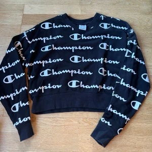 Svart croppad tröja Champion - Säljer en svart croppad tröja från Champion med deras ikoniska logga i vitt över hela tröjan. Den har långa ärmar och är perfekt för en avslappnad stil. Tröjan är i toppen skick och så skönt material! 79% bomull! 🖤