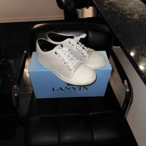 Lanvin skor - Snygga grå/vita sneakers från Lanvin i mycket bra skick. De har en stilren design med vita snören och en vit tåhätta. Perfekta för både vardag och festliga tillfällen. Skorna är bekväma och passar till de flesta outfits. Kommer i originalkartong. Storlek 8/42-43