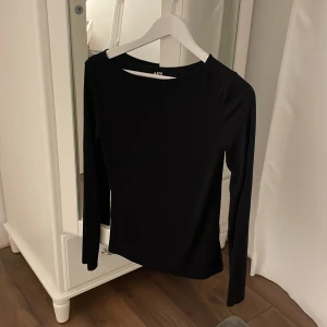 Svart långärmad topp från 157 - Säljer en stilren svart långärmad topp från 157 i storlek S. Den är gjord av mjuk viskos med lite stretch för en bekväm passform. Perfekt för både vardag och fest! 🖤