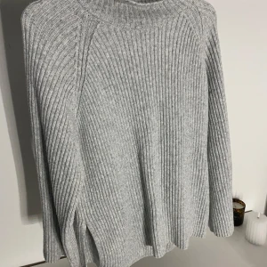 Grå ribbad polotröja - Säljer en supermysig grå ribbad polotröja i mycket bra skick. Perfekt för kyliga dagar med sin höga krage och långa ärmar. Tröjan är både stilren och bekväm, idealisk för höst och vinter. Passar perfekt till jeans eller kjol för en avslappnad look.