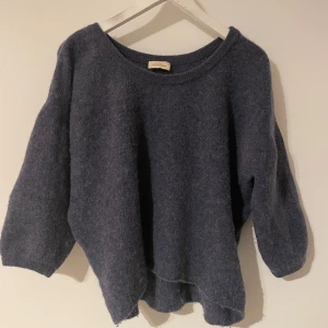 Mörkblå tröja från American Vintage - Säljer en supermysig mörkblå tröja från American Vintage. Den är perfekt för kyliga dagar med sin mjuka och fluffiga textur. Tröjan har en avslappnad passform och trekvartsärmar, vilket gör den både bekväm och stilren. Passar perfekt till både jeans och kjol! Nypris 1200kr