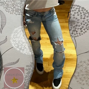 Ljusa slitna jeans - Säljer ett par ljusa jeans med snygga slitningar på knäna. De har en låg midja och en straight passform som ger en avslappnad look. Perfekta för en casual outfit, kanske med en t-shirt eller hoodie. Passar bra till sneakers eller boots.