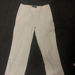 Vita byxor - Säljer ett par vita linnebyxor i bra skick. De är relativt lågmidjade och har en straight passform. Perfekta för både vardag och festliga tillfällen. Passar bra till en enkel topp eller en mer dressad outfit. Bara använd en gång då de är lite korta på mig som är 177