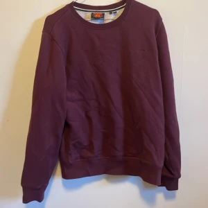 Vinröd tröja från Superdry - Säljer en snygg vinröd tröja från Superdry. Den är i bra skick och perfekt för höst och vinter. Tröjan har långa ärmar och en klassisk rund halsringning. Perfekt för en casual look eller att mysa i hemma. Storleken är inte angiven men den ser ut att vara normal i passformen.