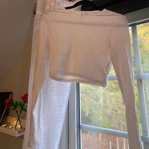 Vit långärmad topp från H&M Divided - Säljer en vit långärmad topp från H&M Divided i storlek S. Toppen är croppad och perfekt för både vardag och fest. Tröjan är i ett rätt så tunt material så perfekt att ha på sena sommarkvällar! Använd sällan🌟