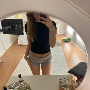 Svart kortärmad topp med öppen rygg - Snygg svart topp med korta ärmar, en bred halsringning och öppen rygg. Perfekt för både vardag och fest. Materialet är mjukt och stretchigt, vilket ger en bekväm passform.