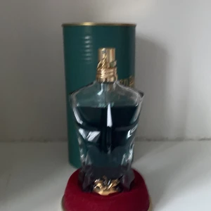 Jean Paul Gaultier Le Beau parfym - Säljer en cool parfymflaska formad som en manlig torso från Jean Paul Gaultier. Flaskan är mörkblå med en guldig kork och kommer i en snygg grön metallförpackning. Perfekt för den som vill ha en unik och stilren doft på hyllan. Passar både till vardags och fest! Kan snacka pris om man vill 