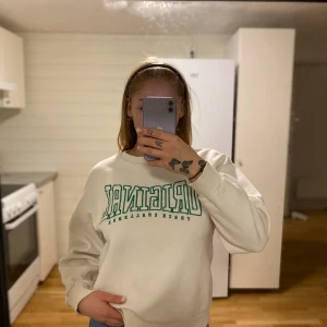 Vit sweatshirt från Gina Tricot - Säljer en vit sweatshirt från Gina Tricot med texten 'ORIGINAL TRACK CHALLENGE' i grönt på framsidan. Tröjan har en normal passform och är perfekt för en avslappnad stil. Den är i mycket bra skick. 