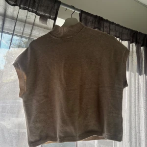 Beige stickad väst - Säljer en snygg beige stickad väst med ribbad krage och ärmslut. Perfekt för lager-på-lager under hösten eller våren. Västen har en enkel och stilren design som passar till det mesta. Den är i bra skick och redo för en ny ägare!