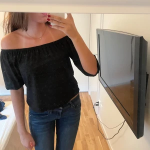 Svart off-shoulder topp - Säljer en snygg svart topp. Den går också att ha off-shoulder och har ett fint mönster i tyget.  Toppen är i bra skick!