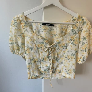 Blommig topp med snörning - Blommig topp med snörning, kan dras ihop för mindre urringning.