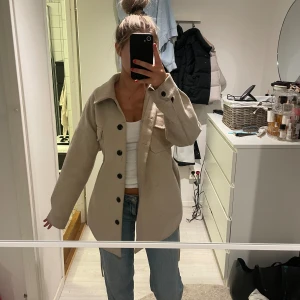 Beige Kappa från Nelly  - Beige Kappa från Nelly i storlek 34/36💕 Den är använd så den är ganska nopprig men inget man tänker på från håll💞 man ser de på tredje bilden ☺️ man kan även knyta den 
