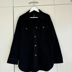 Svart overshirt från Lindex - Säljer en snygg svart jeansjacka/overshirt från Lindex. Perfekt nu i höst med tjockare tröja under. Oversize fit.
