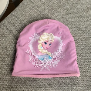 En lilla mösa med Elsa på - Storlek 52-54. Den e lilla med Elsa på varm inuti