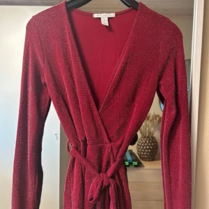 VinRöd glittrig omlott topp / blus - Säljer en superfin röd glittrig omlott topp från Nelly. Den har långa ärmar och ett knytband i midjan för en snygg passform. Perfekt för både festliga och vardagliga tillfällen! ✨