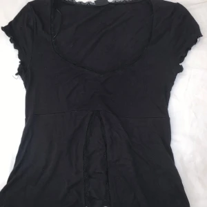 Svart topp gina tricot  - Gullig svart topp från gina tricot, har en öppning under bysten. Storlek S Använd endast någon enstaka gång 