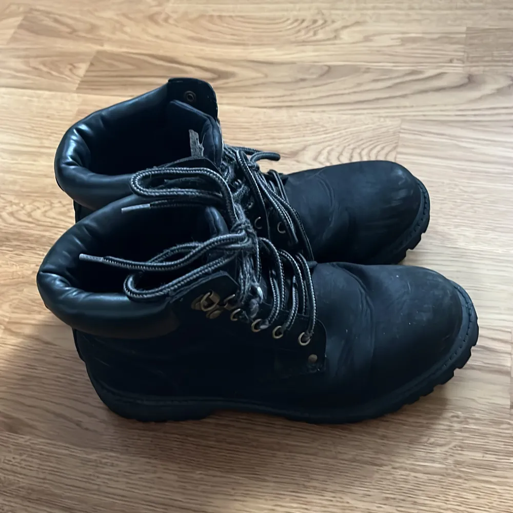 Säljer ett par svarta boots med snörning. De har en robust sula och metallöglor för snörena. Perfekta för höst och vinter, och de ger en cool look till vilken outfit som helst. Lite slitna men fortfarande i bra skick!. Skor.