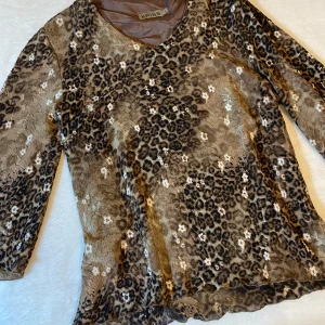 Blus med leopard mönster - En blus med leopard mönster och små blommor som detaljer