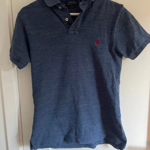 Blå pikétröja från Ralph Lauren - Snygg raffe piké perfekt under tröjan eller till när det blir lite varmare. Inga defekter och snabb frakt. Pris inte hugget i sten🤩🤩