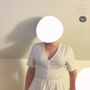 Vit klänning från Gina Tricot - Säljer en superfin vit topp från Gina Tricot i storlek S. Den har en v-ringad design och korta ärmar, perfekt för sommardagar. Materialet är ribbat vilket ger en snygg struktur och passformen är normal. Toppen är enkel men stilren.